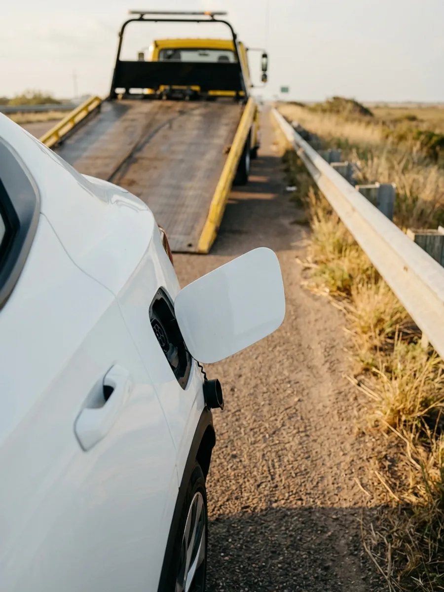 Close up of an electric car's open charge-port flap on the rear quarter panel on a coastal highway shoulder